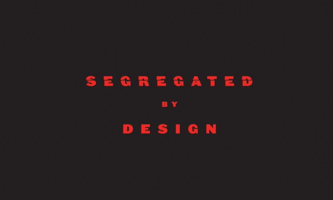 Photo of red text on top of a black background that says "Segregated by Design" with "by" smaller than the other two words and spaced vertically between them.
