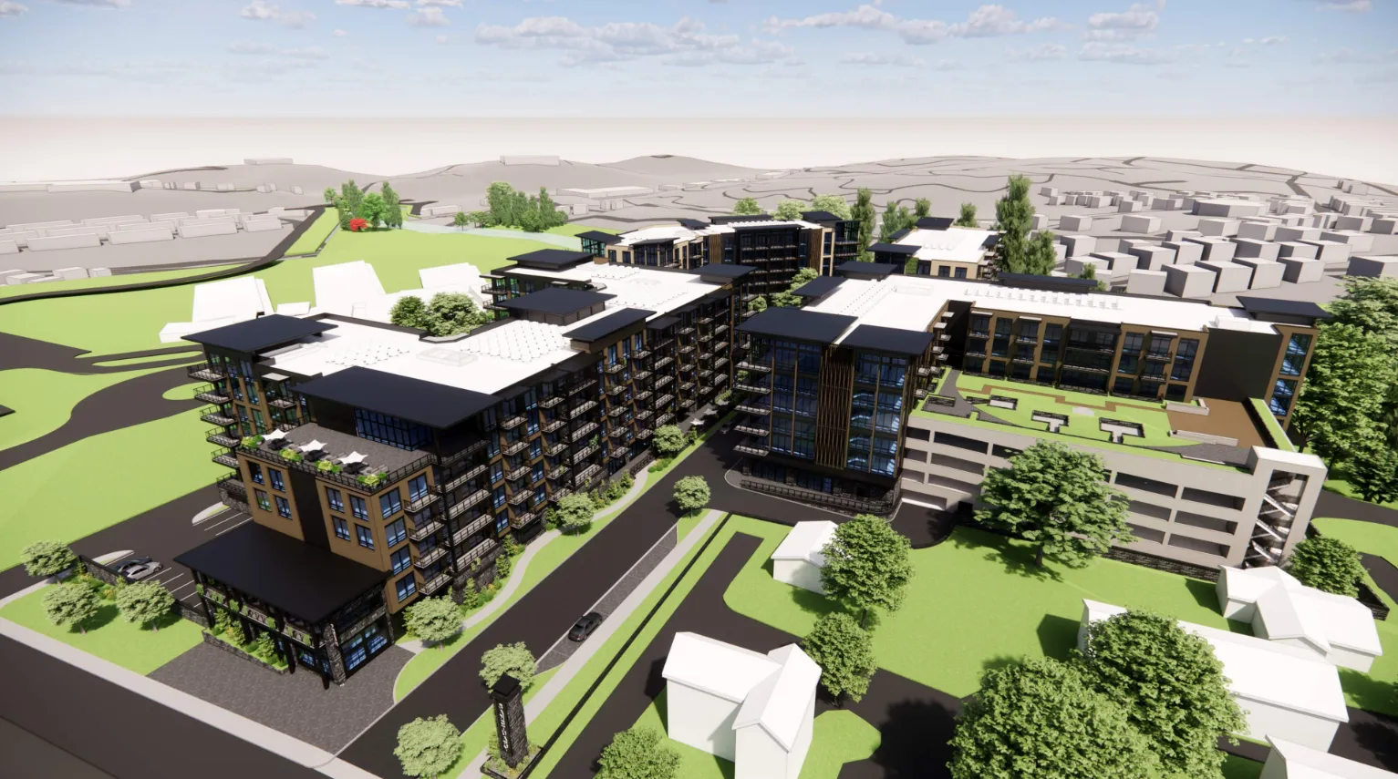 An aerial view of a modern residential development featuring several multi-story buildings with large windows and balconies. The complex is surrounded by green spaces and trees, situated in a suburban area with additional buildings in the background.
