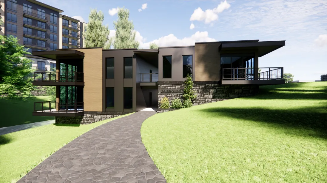 Modern house with flat roof and large windows, surrounded by a lush green lawn. A stone pathway leads to the entrance. Tall trees and a multi-story building are in the background under a partly cloudy sky.